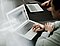 Mann sitzt vor einem Laptop und scrollt auf dem Touchpad