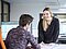 Mann vor einem Bildschirm im Büro bespricht sich mit einer stehenden Frau auf der anderen Seite des Tisches 
